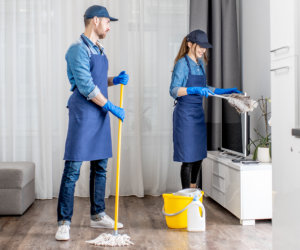 Two individuals in blue overalls diligently cleaning a large window