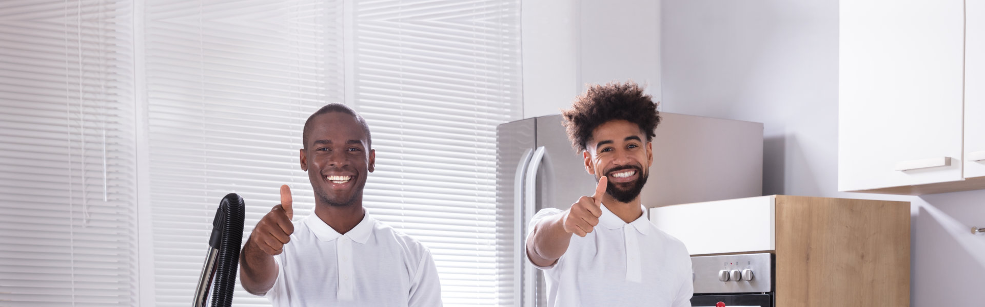 Two men dressed in white shirts are positioned in a kitchen