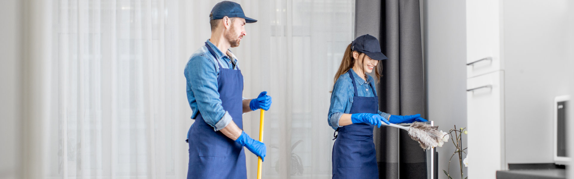 Two individuals in blue overalls diligently cleaning a large window